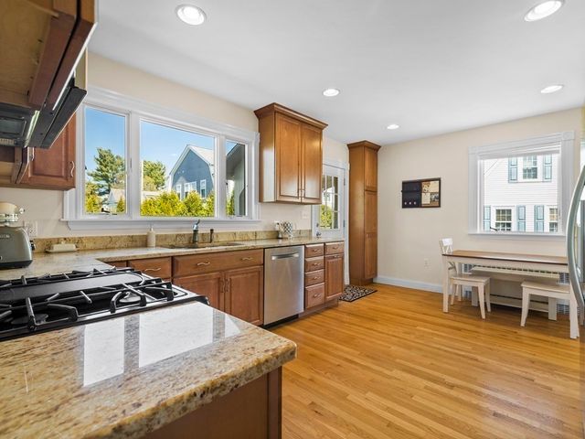 a kitchen with stainless steel appliances granite countertop a stove a sink dishwasher and a refrigerator with wooden floor