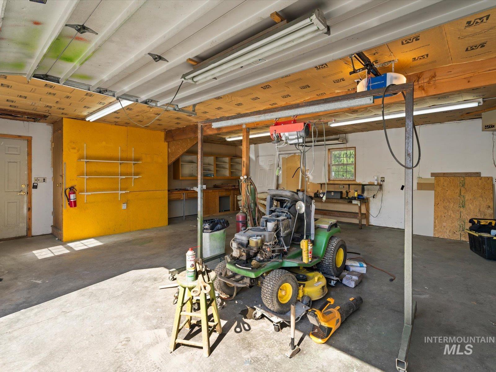 3540 Wills Road Emmett, ID 83617 - Photo 28 of 36 Spacious utility building featuring a concrete floor, exposed wood beam ceiling, multiple fluorescent light fixtures, and workbench area with built-in cabinetry