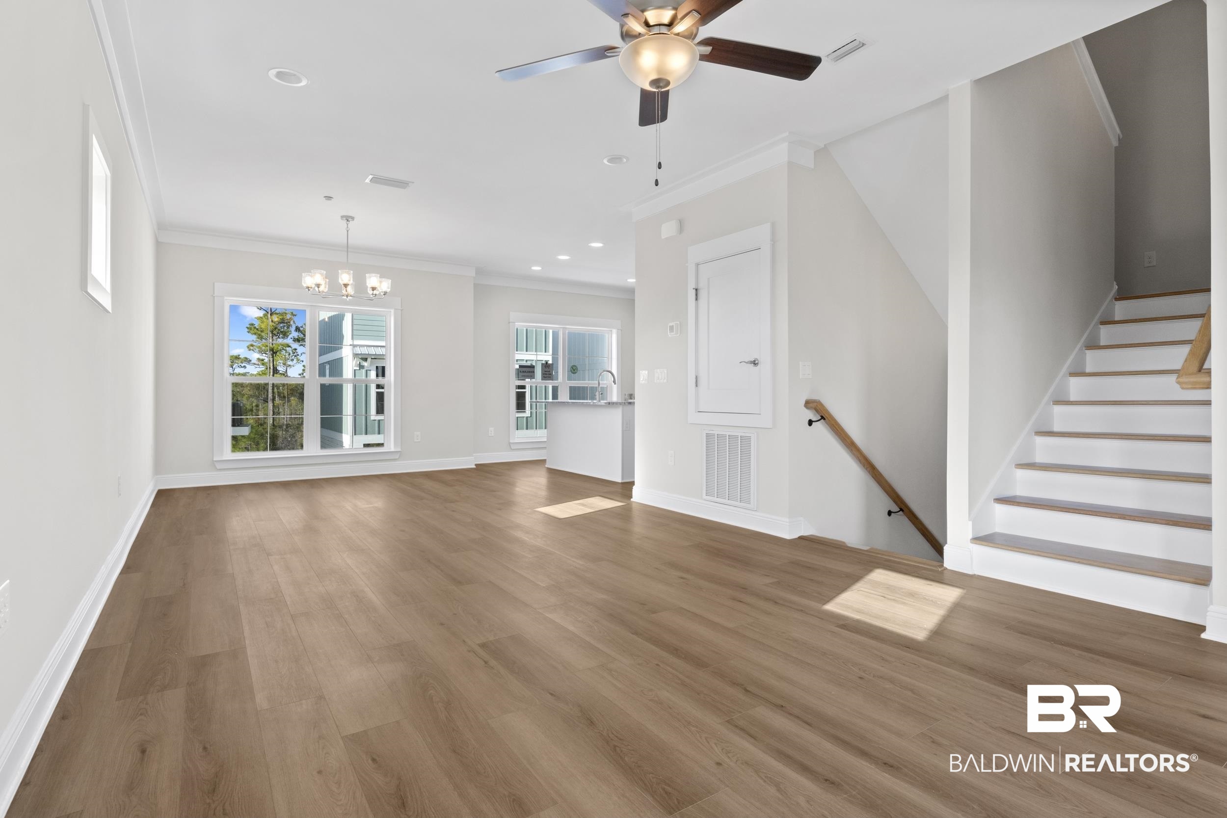 2847 Salt Drive Orange Beach, AL 36561 - Photo 6 of 29 Unfurnished living room featuring hardwood / wood-style floors, ceiling fan with notable chandelier, and ornamental molding
