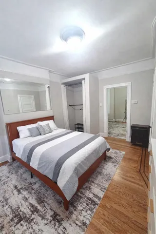 a spacious bedroom with a bed and wooden floor