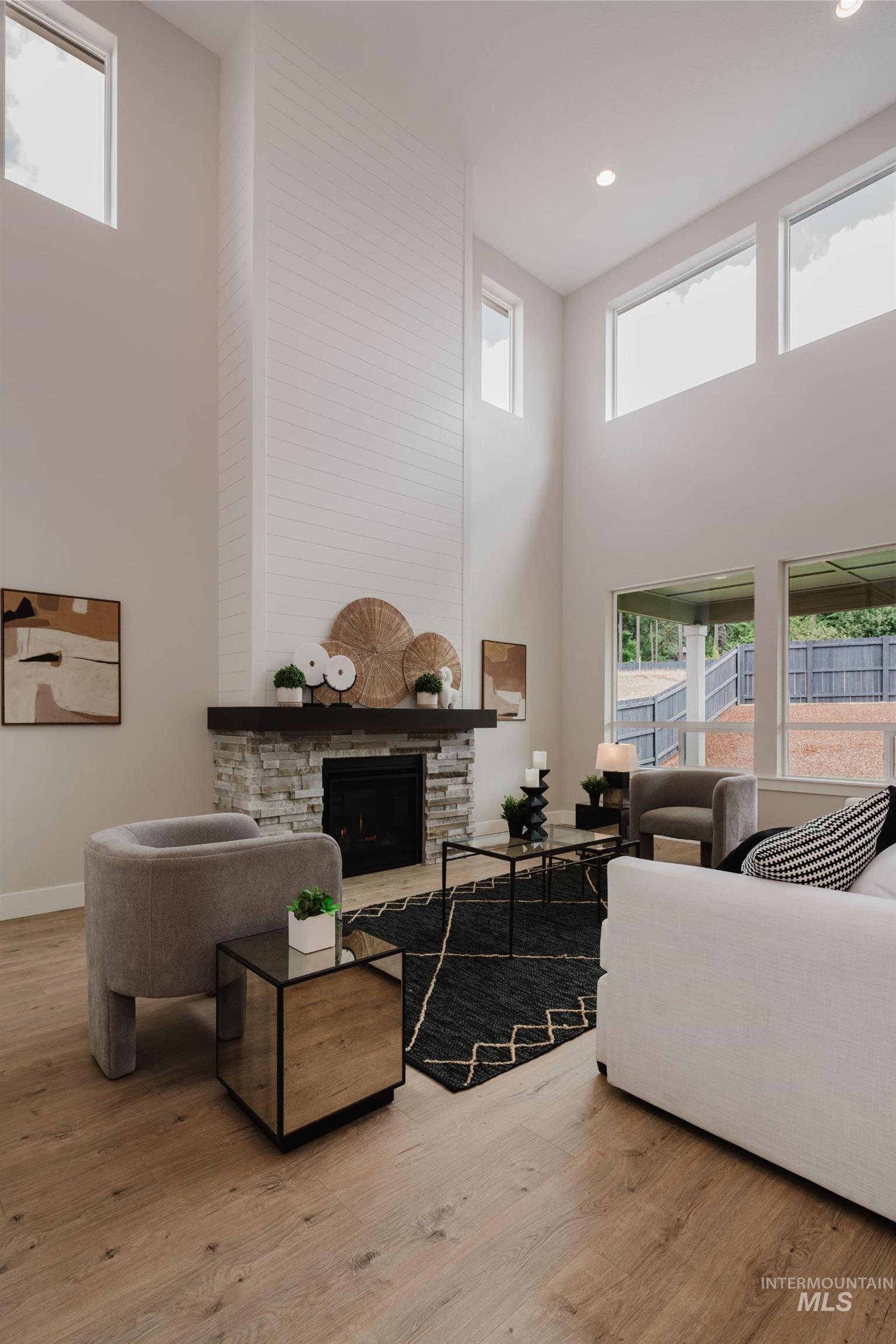 2866 North Stone Mill Avenue, Unit ROUGE Eagle, ID 83616 - Photo 12 of 18 Living area featuring a high ceiling, a fireplace, and light wood-style floors