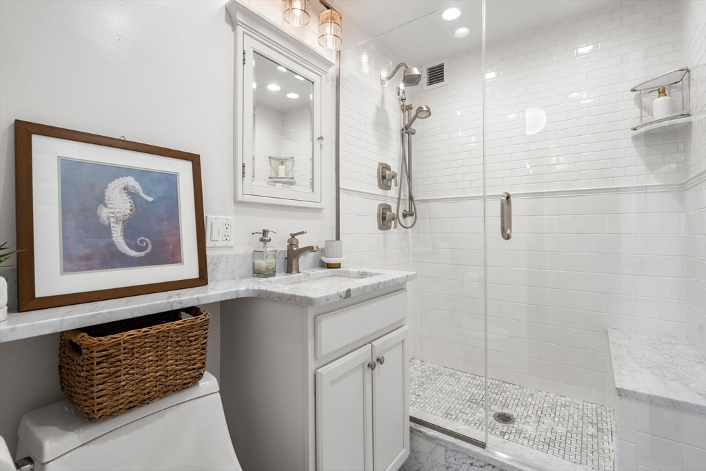 85 East India Row, Unit 19H Boston, MA 02110 - Photo 17 of 23 a bathroom with a granite countertop sink a shower and a mirror
