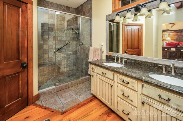 a kitchen with stainless steel appliances granite countertop a stove top oven a refrigerator a sink and dishwasher with wooden floor