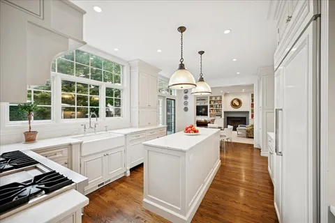 a large kitchen with kitchen island a stove a counter top a chandelier and a view of living room