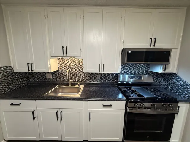 a kitchen with a stove and white cabinets