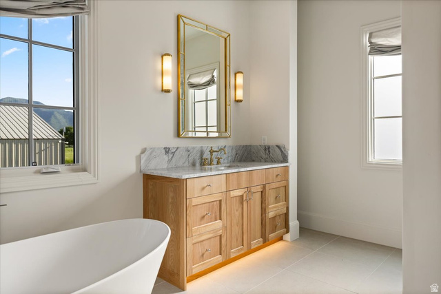 478 South Maple Lakes Drive Mapleton, UT 84664 - Photo 23 of 51 Freestanding soaking tub with a light wood-finish vanity, marble countertop, and gold-framed mirror