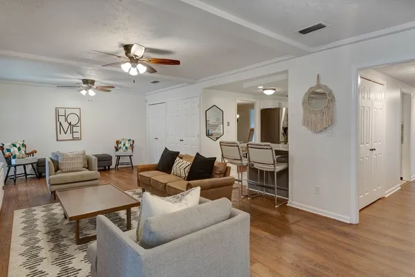 a living room with furniture a large window and wooden floor