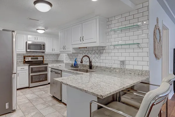 a kitchen with stainless steel appliances granite countertop a sink dishwasher a stove top oven a refrigerator and dishwasher