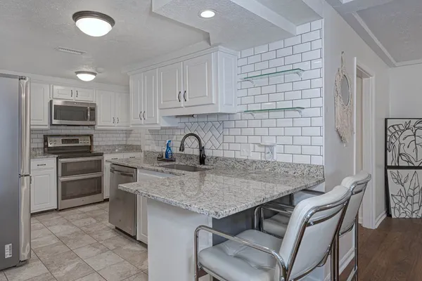 a kitchen with stainless steel appliances granite countertop a sink stove and refrigerator