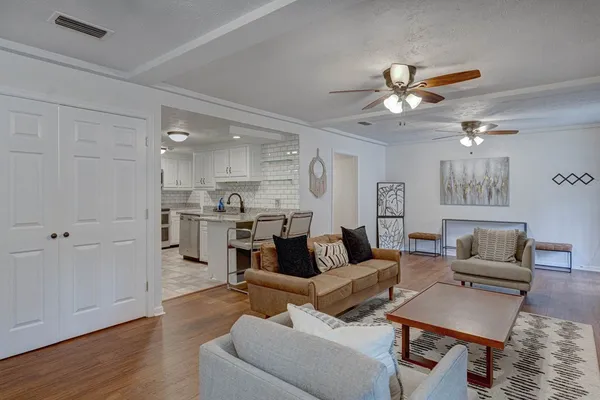 a living room with furniture kitchen view and a wooden floor