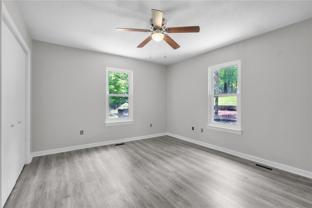 48 Tierra Drive Waterloo, SC 29384 - Photo 33 of 42 Double windows frame leafy backyard views in this peaceful bedroom with wood-look flooring.
