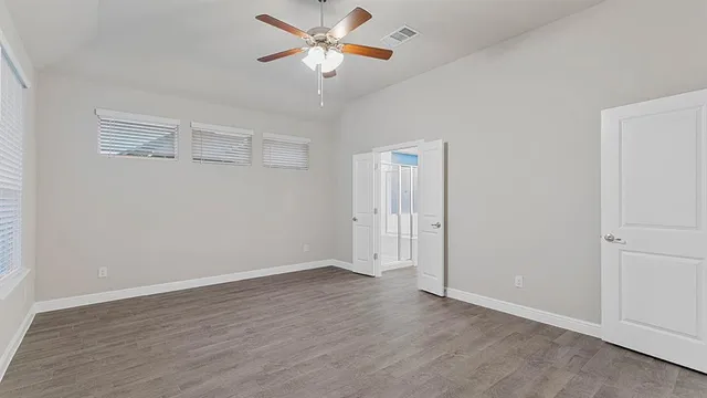 an empty room with wooden floor closet and fan