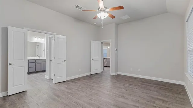 an empty room with wooden floor and ceiling fan