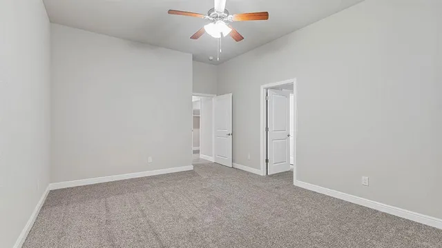 an empty room with closet and a chandelier fan