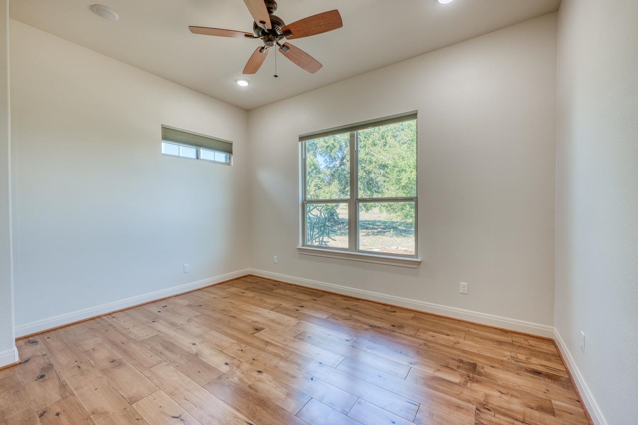 229 Eagle Ridge Burnet, TX 78611 - Photo 24 of 30 an empty room with wooden floor fan and windows