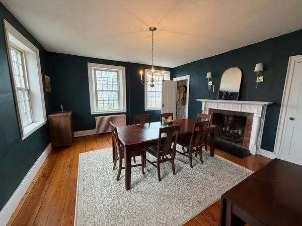 a dining room with furniture a rug a fireplace and wooden floor