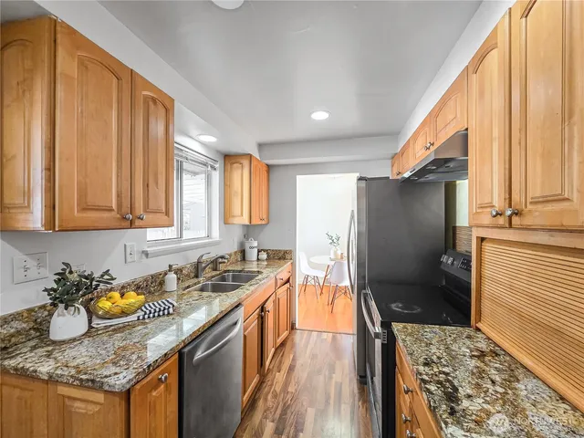 a kitchen with granite countertop a sink stove and refrigerator