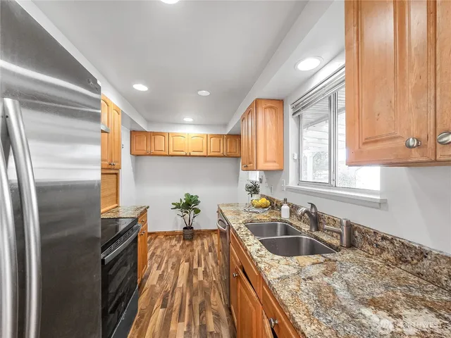a kitchen with granite countertop a sink a counter top space stainless steel appliances and cabinets