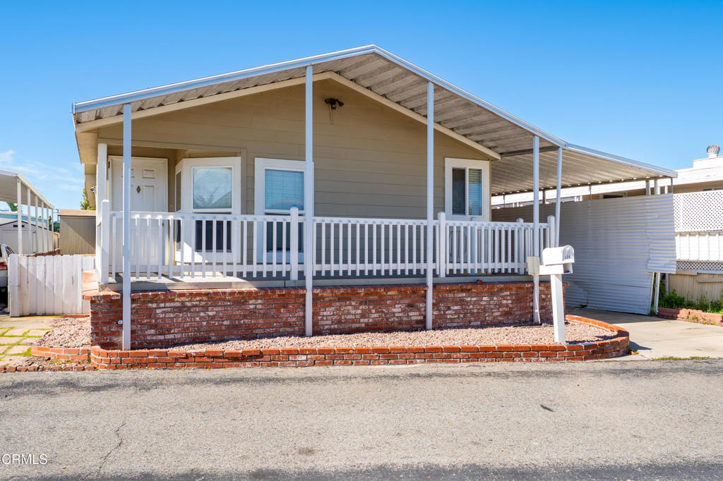 2400 East Pleasant Valley Road, Unit 108 Oxnard, CA 93033 - Photo 2 of 29 a view of a house with a small yard and wooden fence and a floor to ceiling window
