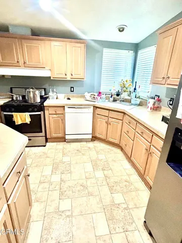 a large kitchen with stainless steel appliances a stove a sink a counter space and cabinets