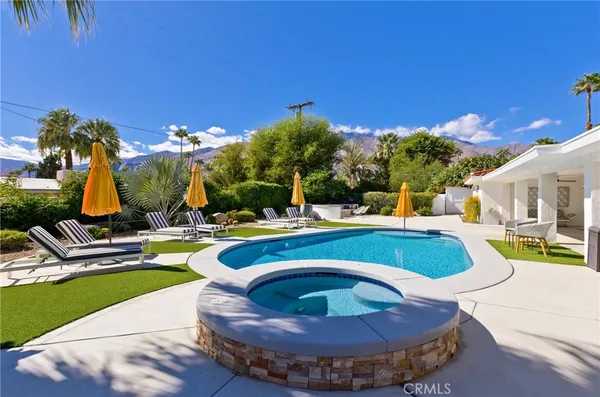 a view of swimming pool with outdoor seating and house in the background