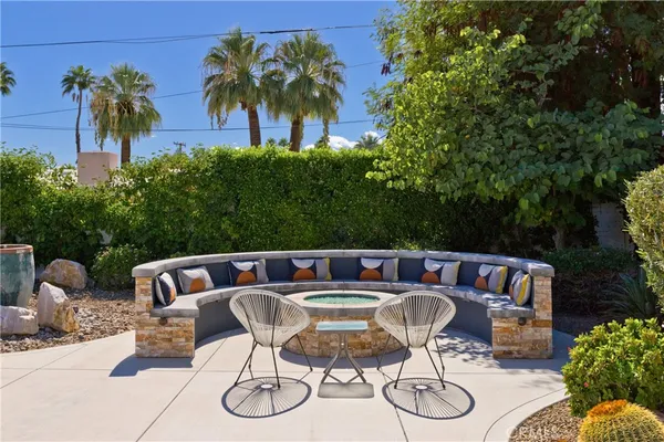 a patio table and chairs with potted plants and large trees