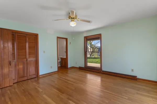 an empty room with wooden floor closet and windows