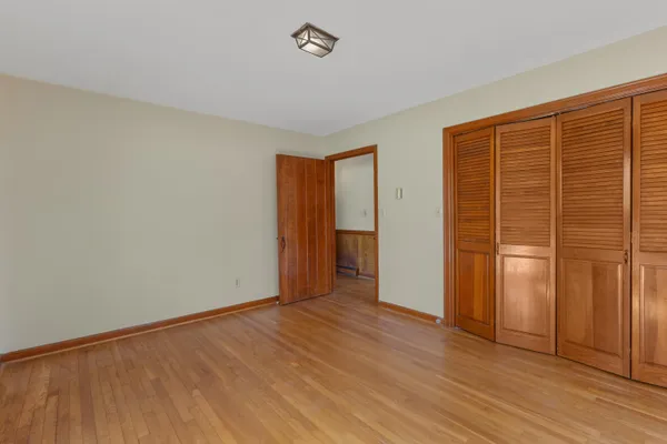 an empty room with wooden floor and closet area