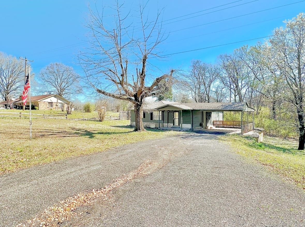 Single story home with a front lawn, aphalt driveway, and a carport