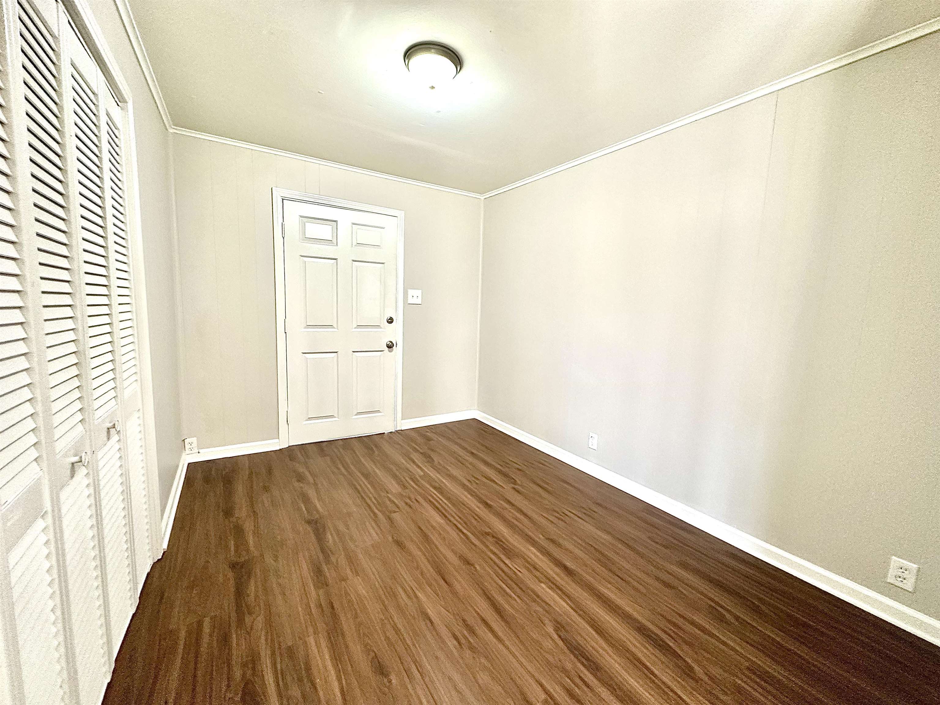 Interior space featuring a closet, ornamental molding, baseboards, and wood finished floors