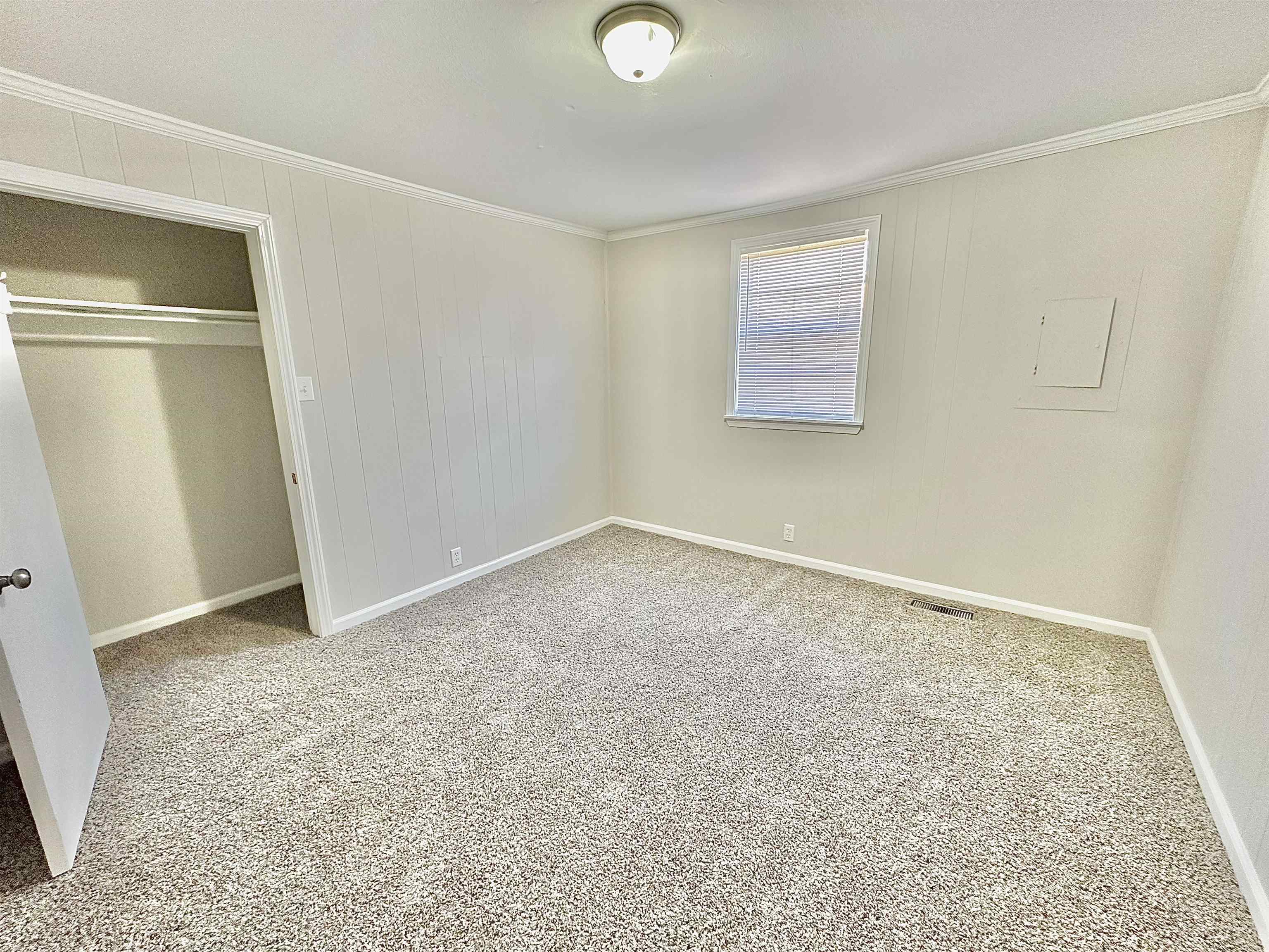 Unfurnished bedroom featuring a closet, visible vents, carpet, and ornamental molding