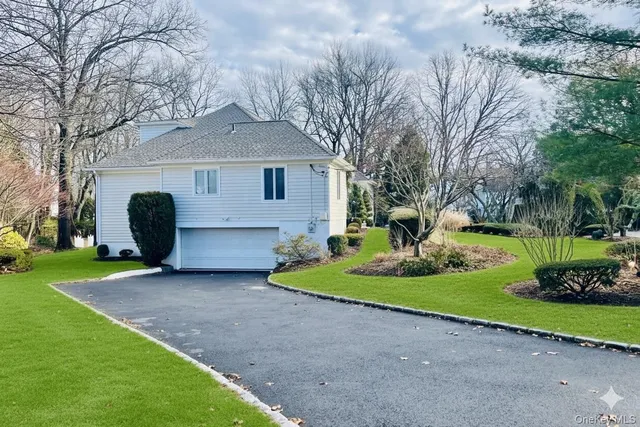 a view of a house with a yard and a large tree