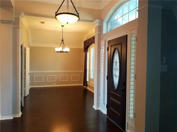 a view of a hallway with wooden floor and chandelier