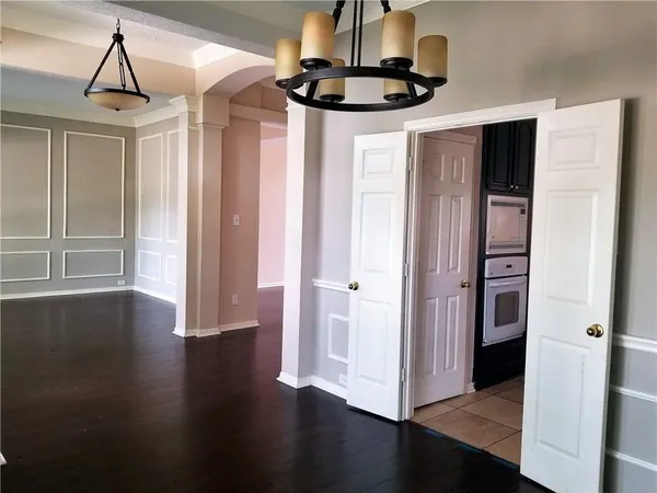 a view of a hallway with wooden floor and chandelier