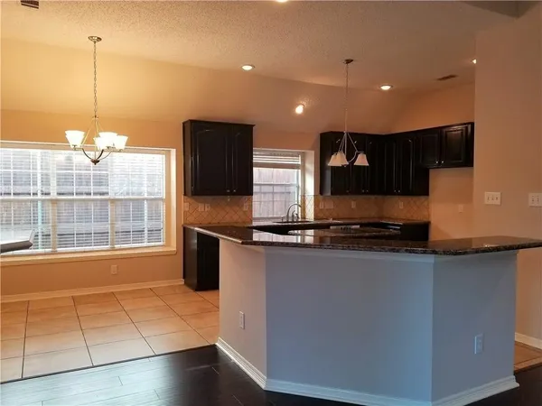 a large kitchen with stainless steel appliances a large counter top a stove a sink and a refrigerator