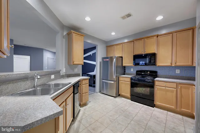 a kitchen with stainless steel appliances granite countertop a sink stove refrigerator and cabinets