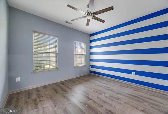 a view of an empty room with a window and a chandelier fan