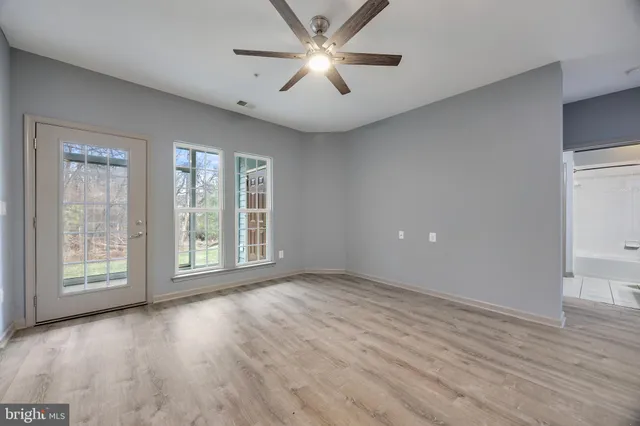 a view of an empty room with window and wooden floor