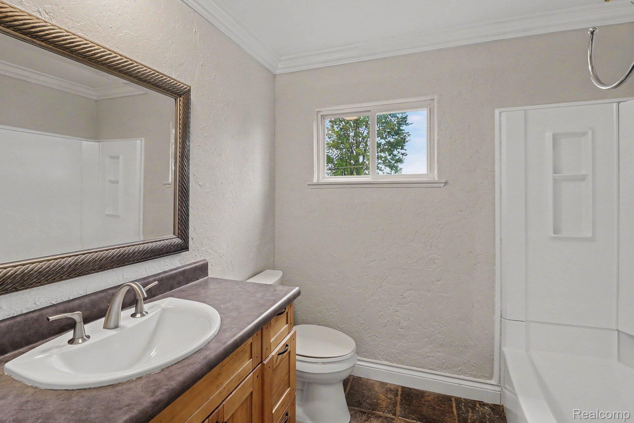 905 North Wilder Road Lapeer, MI 48446 - Photo 15 of 15 Bathroom featuring a vanity with an undermount sink, a framed mirror, a toilet, a shower/tub combination, and a window