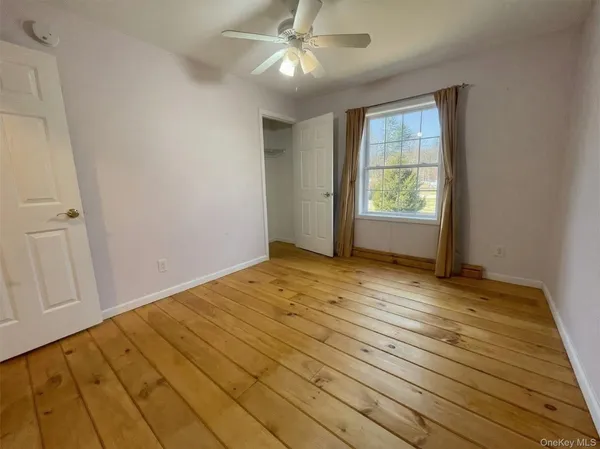 a view of empty room with wooden floor and fan