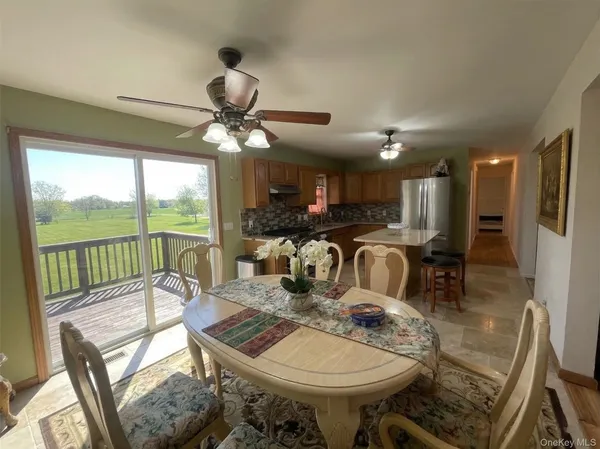 a view of a dining room with furniture a chandelier and large windows