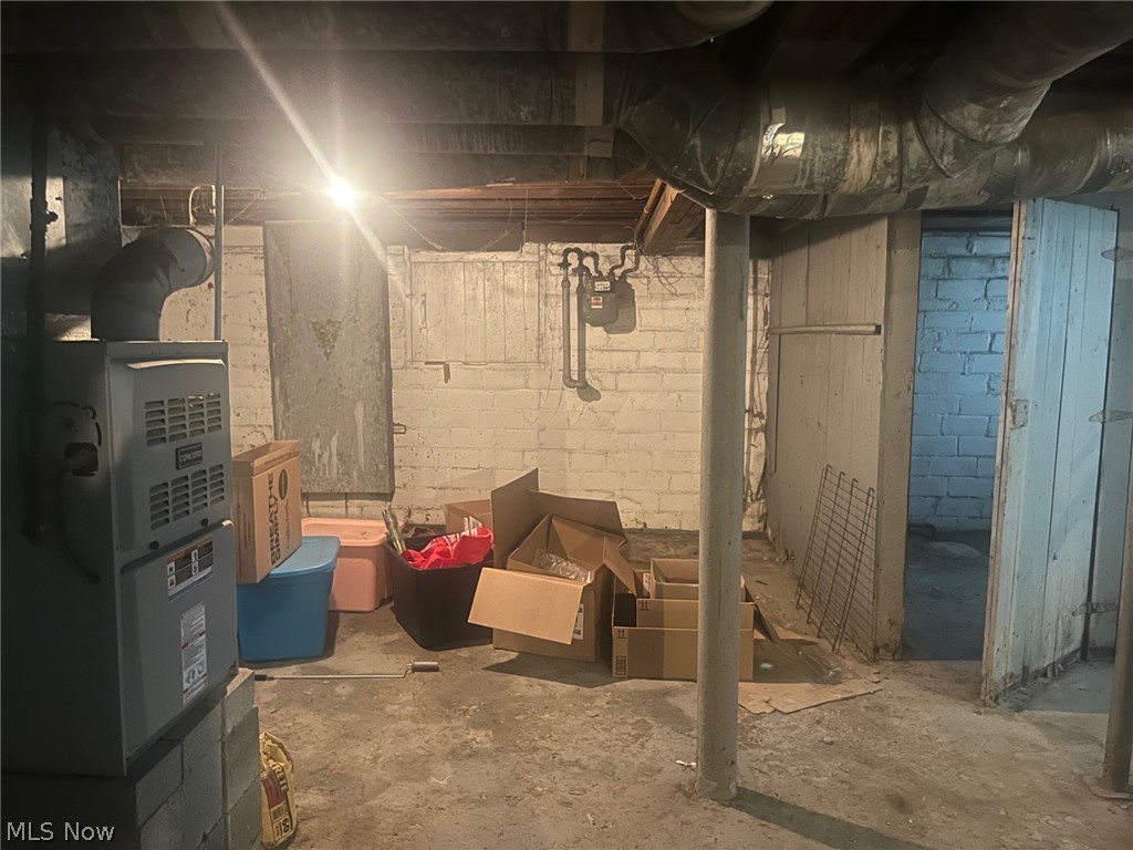 1101 Carlyon Road East Cleveland, OH 44112 - Photo 21 of 23 Utility area featuring exposed ceiling joists, concrete flooring, and painted brick walls