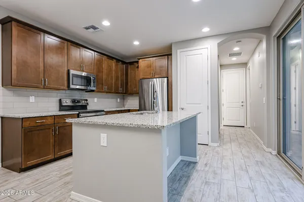 a kitchen with stainless steel appliances granite countertop wooden cabinets a refrigerator and a stove top oven