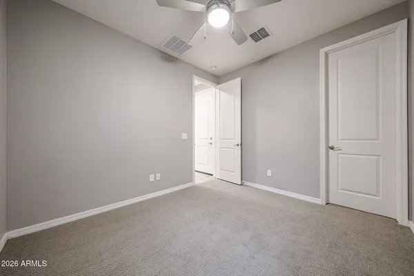 an empty room with a chandelier fan and windows