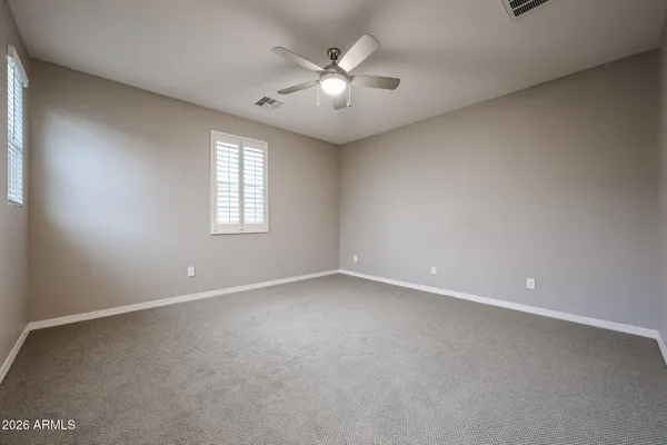 an empty room with windows and ceiling fan