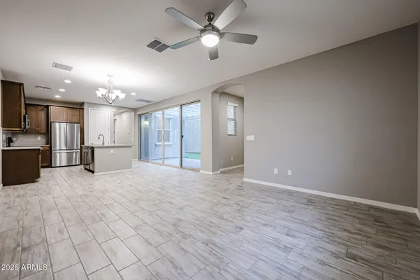 a view of an empty room with kitchen and window