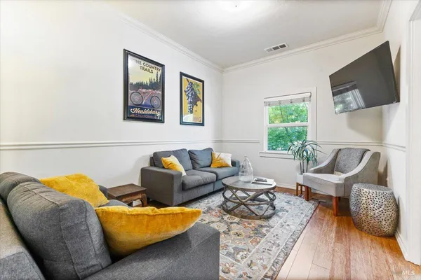 a kitchen with granite countertop a refrigerator a stove a sink dishwasher and white cabinets with wooden floor