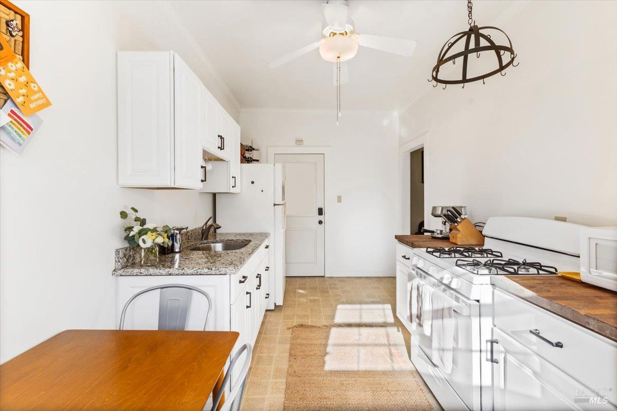 320 Center Street Healdsburg, CA 95448 - Photo 37 of 56 a kitchen with stainless steel appliances granite countertop a stove a sink dishwasher and white cabinets with wooden floor