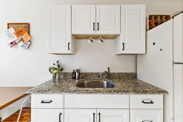 a kitchen with stainless steel appliances granite countertop a stove and a view of living room