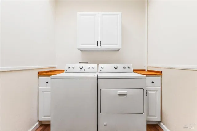 a bedroom with a bed and dresser with paintings on wall